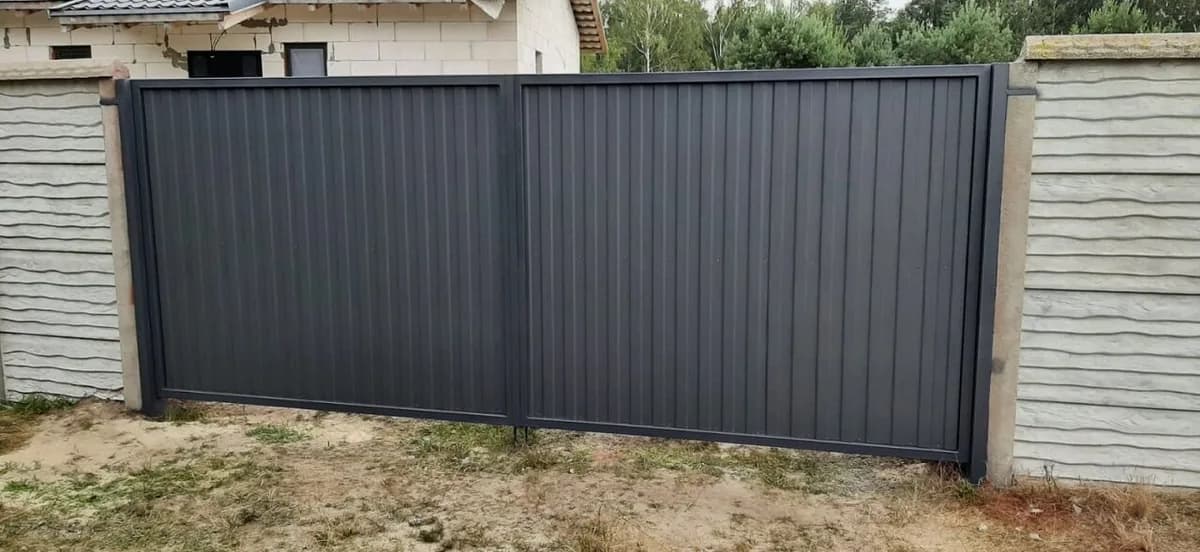 Серые распашные ворота между бетонными столбами